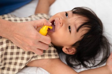 Anne ya da doktor küçük kızın ağzına ilaç sıkıyor. bebek boğaz ağrısı konsepti