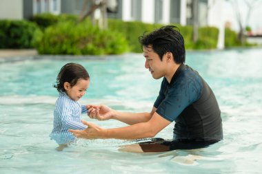 Mutlu baba ve bebek yüzme havuzunda oynuyorlar