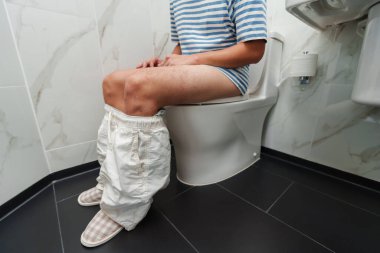 Tuvaletteki klozete yakın oturan adam.