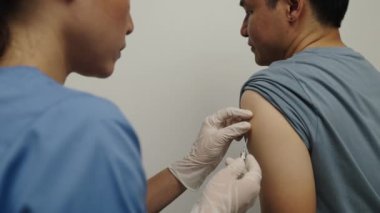 Eldivenli doktor şırınga tutuyor ve hastaya aşı yapıyor.