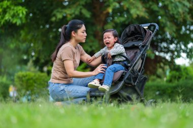 Anne, bebeğini teselli ediyor. Bebek arabasında ağlıyor.