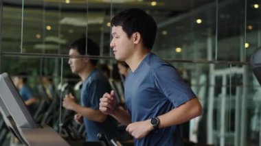 Spor salonunda koşu bandında koşan genç adamın yavaş çekimi.
