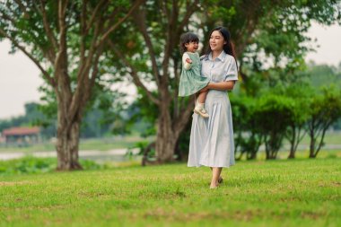 Anne kucağında ağlayan bebek bebek parkta çimlerde yürürken