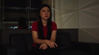 Şok olmuş ve korkmuş bir kadın geceleri bir kanepede korku filmi izliyor.