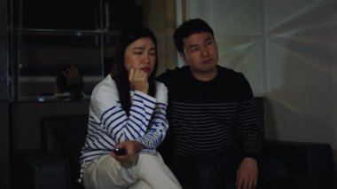 Geceleri kanepede oturup romantik film izleyen ağlayan bir çift.