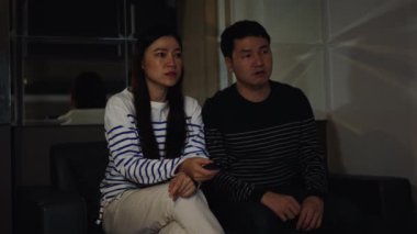 Şok olmuş ve korkmuş çift geceleri bir kanepede korku filmi izliyor.