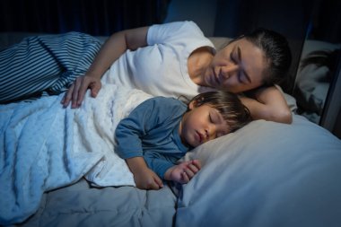 Anne, yeni yürümeye başlayan bebeği kucaklar ve geceleri yatakta birlikte uyur.