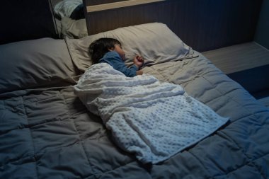 Küçük bebek geceleri bir yatakta uyuyor.