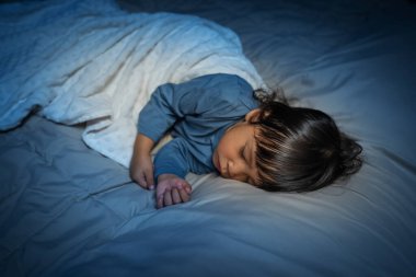 Küçük bebek geceleri bir yatakta uyuyor.