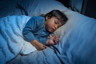 Küçük bebek geceleri bir yatakta uyuyor.