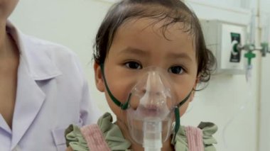 Doktor, bebek bir bebeğe ilaç tedavisi uyguluyor. Hastanede nebulizör maskeli bir çocuk