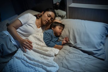 Anne, yeni yürümeye başlayan bebeği kucaklar ve geceleri yatakta birlikte uyur.