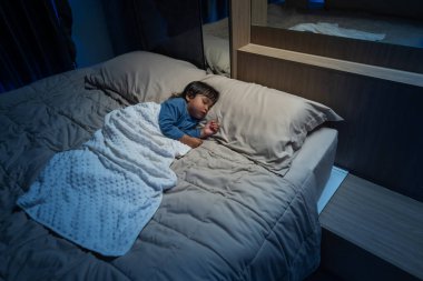 Küçük bebek geceleri bir yatakta uyuyor.