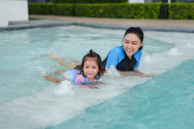 Bebekli anne havuzun kenarında yüzmeyi öğreniyor.