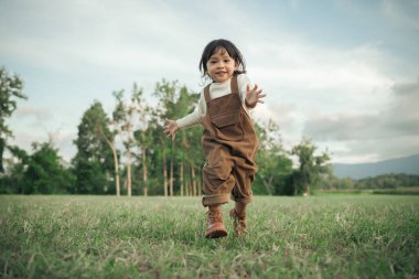 Çimenlikte koşan mutlu küçük kız.