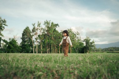 Mutlu küçük kız çimlerde yürüyor.