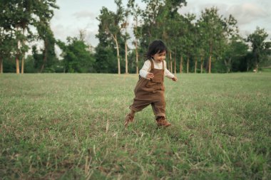 Çimenlikte koşan mutlu küçük kız.