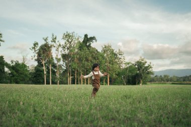 Çimenlikte koşan mutlu küçük kız.