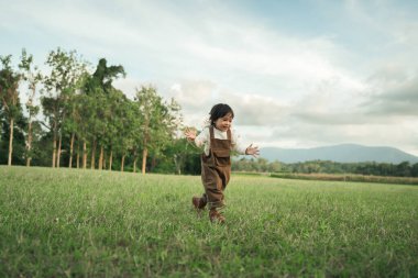 Çimenlikte koşan mutlu küçük kız.