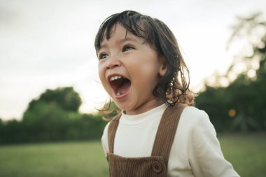 Neşeli küçük kız çim tarlasında gülüyor