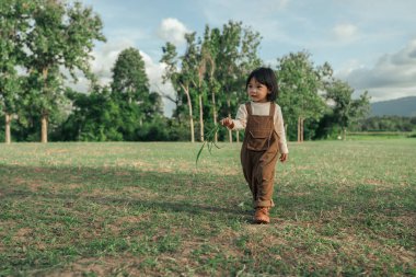 Mutlu küçük kız çimlerde yürüyor.