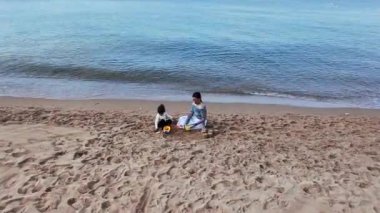 Pattaya, Tayland 'da kumsalda annesiyle kum oyuncağı oynayan küçük kızın hava manzarası.