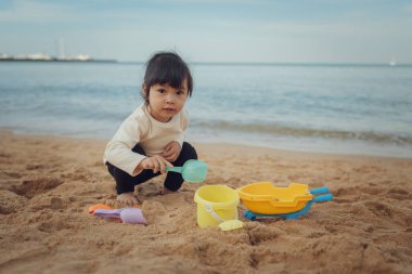 Küçük bebek Tayland, Pattaya 'da kumsalda kum oyuncağı oynuyor.