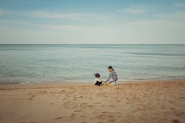 Küçük mutlu kız Pattaya, Tayland 'da annesiyle kumsalda kum oyuncağı oynuyor.