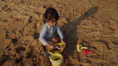 Pattaya, Tayland 'da kumsalda kumlarla oynayan mutlu bir bebek.