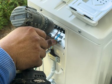 İşçi, klimanın kurulumuna elektrik kablolarını bağlıyor