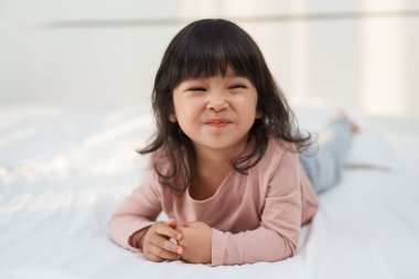 Mutlu küçük kız yatakta gülümsüyor.