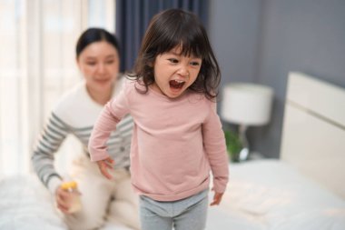 Anne ve bebek bir yatakta oynayıp dans ediyorlar.