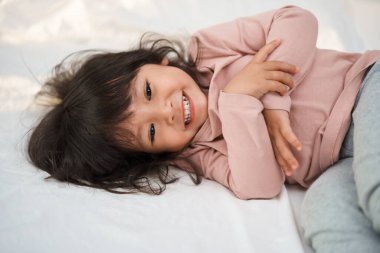 Mutlu küçük kız yatakta gülümsüyor.