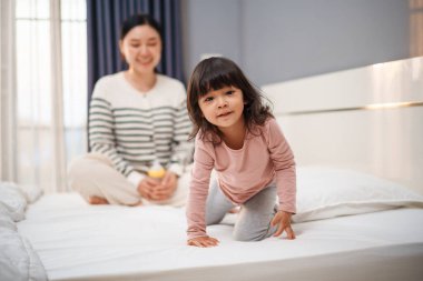 Annesiyle birlikte yatakta mutlu bir bebek.