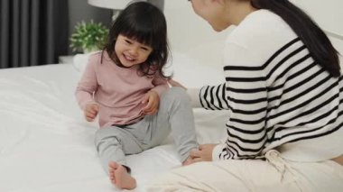 Neşeli anne ve küçük kız bir yatakta oynuyorlar.