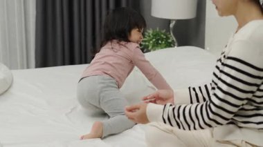 Neşeli anne ve küçük kız bir yatakta oynuyorlar.