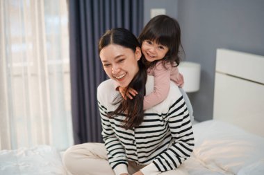 Yavru bebek, annesiyle birlikte bir yatağın üstünde sırt sırta biniyor.