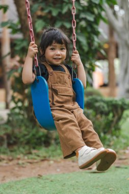 Neşeli küçük kız salıncakta oynuyor