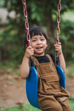 Neşeli küçük kız salıncakta oynuyor