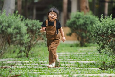 Mutlu küçük kız bahçede taş bir yolda yürüyor.