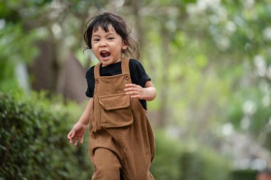 Mutlu küçük kız bahçede koşuyor.