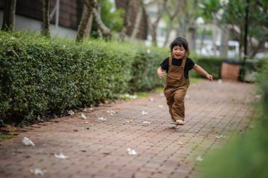 Mutlu küçük kız bahçede bir patikada koşuyor.
