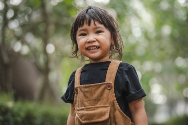 Mutlu gülümseyen küçük bir kızın portresi yeşil doğası bokeh arka plan