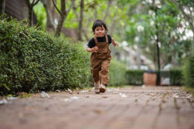 Mutlu küçük kız bahçede bir patikada koşuyor.