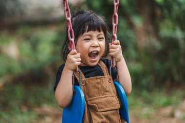 Neşeli küçük kız salıncakta oynuyor