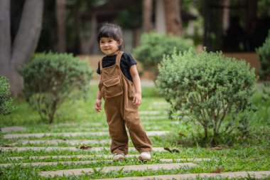 Bahçedeki taş bir patikada duran mutlu küçük kız.