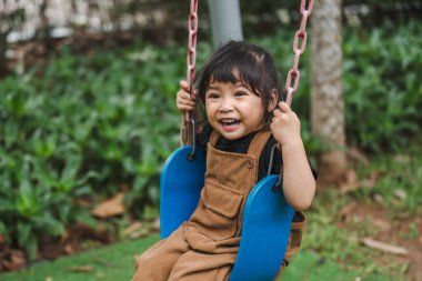 Neşeli küçük kız salıncakta oynuyor