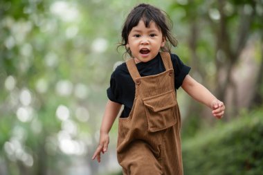 Mutlu küçük kız bahçede koşuyor.
