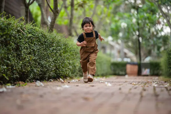 Mutlu küçük kız bahçede bir patikada koşuyor.