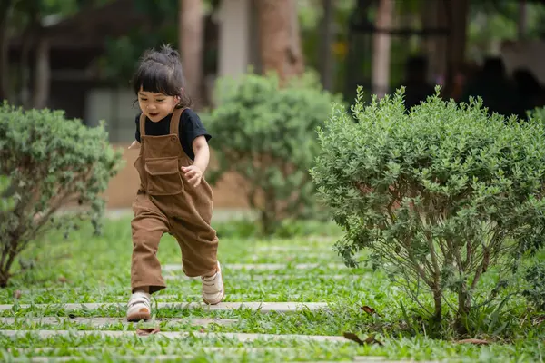 Mutlu küçük kız bahçede taş bir yolda koşuyor.